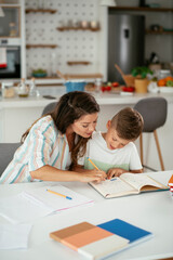 Mother helping her son with homework at home. Little boy learning at home.