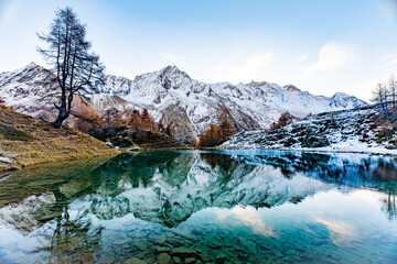 Fototapeta na wymiar Reflections of snow capped mountains in a blue icy lake in the mountains