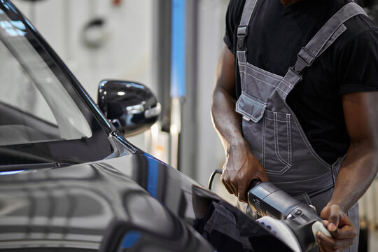 Hardworking Auto Mechanic Male Is Polishing Car With The Use Of Special Equipment, Apply It On Car Surface, Repair And Clean, Renew