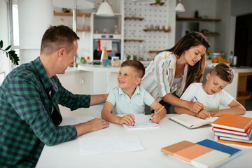 Fototapeta premium Parents helping the kids with their homework. Litlle boys learning at home..