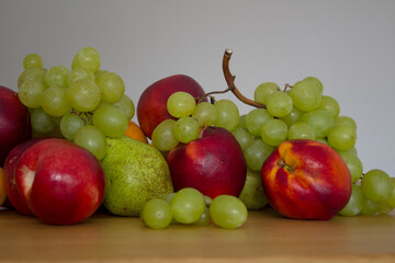 Beautiful fresh fruits on dark grey table: green grapes, nectarines, apricot. Summer fruits top view. 