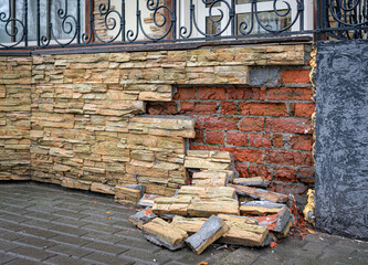 toppled facing material and exposed  brickwork under it