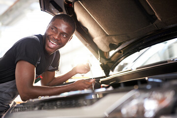 cheerful smiling afro man enjoy repairing car's hood, check the details,fixes machine problems