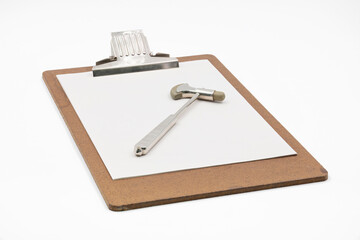 Klemmbrett mit einer Seite Papier und einem Reflexhammer, alte &auml;rztliche Instrumente.