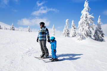 Fototapeta na wymiar Happy little boy learning skiing with his father during winter holidays