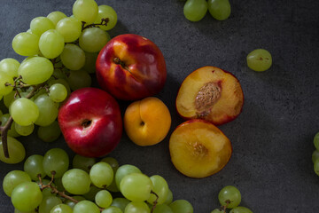 Still life with juicy summer fruits. Top view photo on dark background with copy space. Fresh colorful fruits in a glass vase.