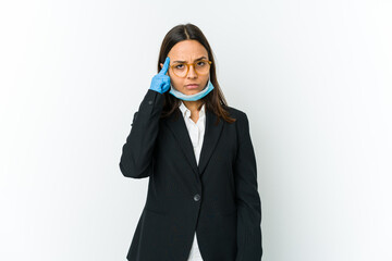 Young business latin woman wearing a mask to protect from covid isolated on white background pointing temple with finger, thinking, focused on a task.