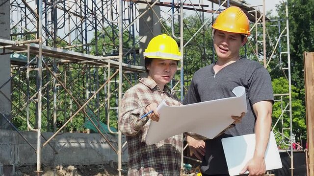 Construction manager and engineer discussing and checking plans on construction site.