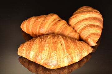 Fragrant homemade croissant, close-up, on a black background.