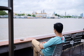 Man relaxing on a chair and enjoying by the river with coffee.