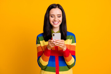 Photo of cheerful young girl smile chat text communicate cellphone mobile isolated over yellow color background