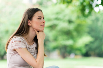 Portrait of pensive woman in park. Large copy-space