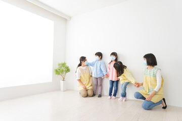 Fototapeta premium マスクを付けて幼稚園で遊ぶ子どもたちの先生