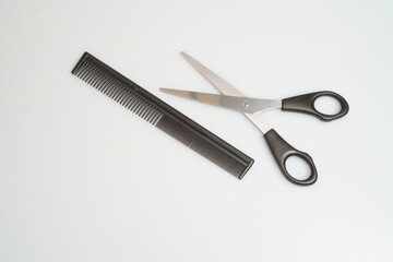 stainless steel scissors with black handle lie and comb on a light table