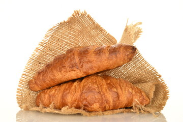 Fragrant homemade croissant on a jute napkin, close-up, on a white background.