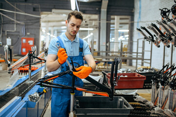 Bicycle factory, worker holds teen bike frame