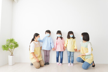 マスクを付けて幼稚園で遊ぶ子どもたちの先生