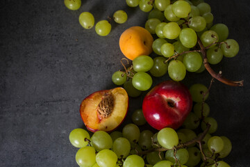 Colorful juicy fruits border.  Fresh summer fruits top view horizontal photo. Dark grey background with copy space. 