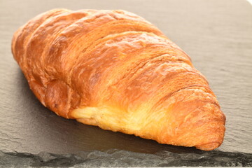 Fragrant homemade croissant, close-up, on a slate board.