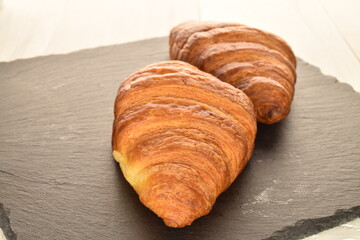 Fragrant homemade croissant, close-up, on a slate board.