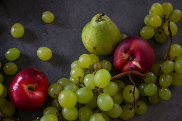 Naklejka na ściany i meble Beautiful fresh fruits on dark grey table: green grapes, nectarines, apricot. Summer fruits top view. 