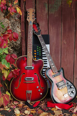 Plakat Two electric guitars and keyboards near the fence with autumn leaves.