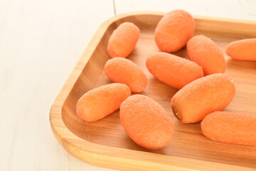 Ripe juicy organic mini carrots, close-up, on a white wooden table.