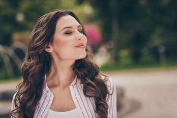 Side profile photo portrait of nice girl with curly hair enjoying fresh wind blowing in city park...