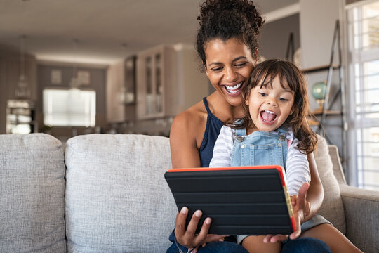 Ethnic mother and little girl having fun with digital tablet