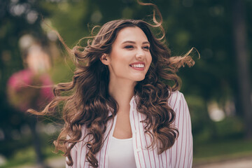 Photo of cute optimistic young woman shiny smiling long curly hair walking park wear white striped...