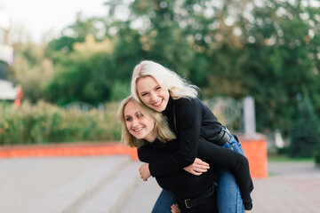 Obraz premium Two young females walking smiling embracing and kissing outdoor in the city