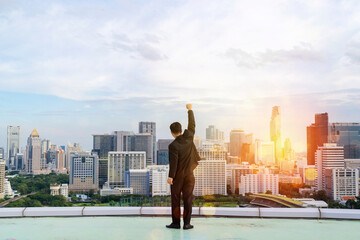 Businessman standing on a roof and looking at city, Raise your hands to express your joy in your accomplishments.