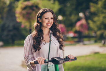 Photo of adorable brunette hair young lady drive segway wear striped shirt enjoy walk in park outside