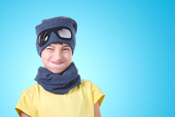 The child took a deep breath wearing a pilot's hat and scarf on a light blue background