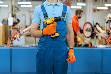 Bicycle factory, worker holds electric screwdriver