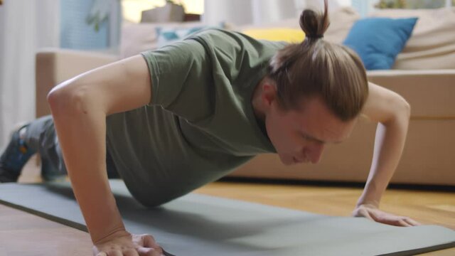 Handsome young man doing daily push up exercise at home.