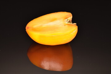 Ripe juicy organic persimmon, close-up, on a black background.