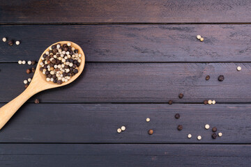 Pepper in wooden spoon placed on a dark vintage wooden table top view