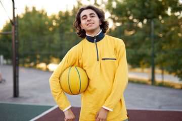 portrait of sportsman young boy with ball, guy came to play basketball after university lessons, have rest, enjoy