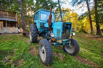 An old blue tractor stands in a farmyard