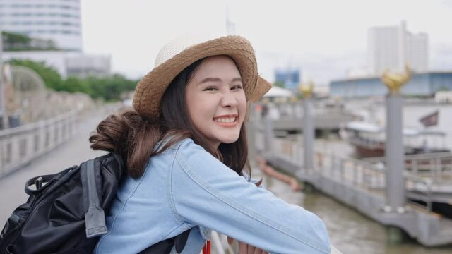 Young Asian woman smile happy to travel during the holidays. Teenage lifestyle Relax during the long weekend. Traveler in a beautiful riverside town. Travel after lockdown