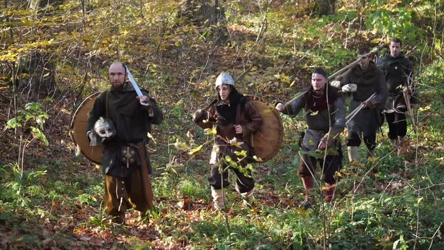 Viking warriors going through the forest after the battle to home. Medieval reenactment.