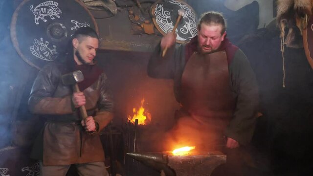 The smith takes the hot metal from the hearth to the anvil and starts hammering. Blacksmith has an effort on glowing hot metal and sparks fly in all directions.