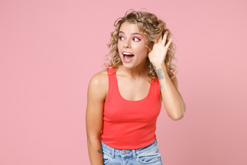 Excited curious young blonde woman 20s wearing basic casual tank top standing try to hear you...