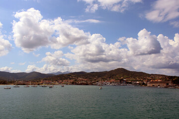 Fototapeta na wymiar La costa di Portoferraio vista dal mare con cielo e nuvole