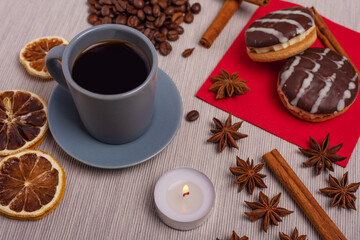 A cup of espresso is decorated with anise stars, cinnamon, sweets, dried lemons, acorns, peanuts in a beautiful dish.