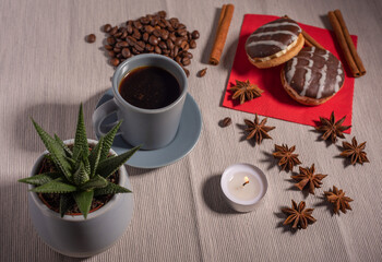 A cup of espresso is decorated with anise stars, cinnamon, sweets, dried lemons, acorns, peanuts in a beautiful dish.