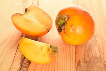 Ripe juicy organic persimmon, close-up, on a wooden table.