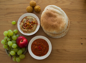 Traditional food of Israel on dark grey background with copy space. Colorful authentic meals top view photo: plate of hummus, falafels, salad, pita bread and tahini sauce. 