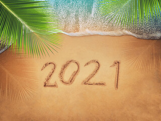 Happy New Year 2021, lettering on the beach with wave and blue sea. Numbers 2021 year on the sea...